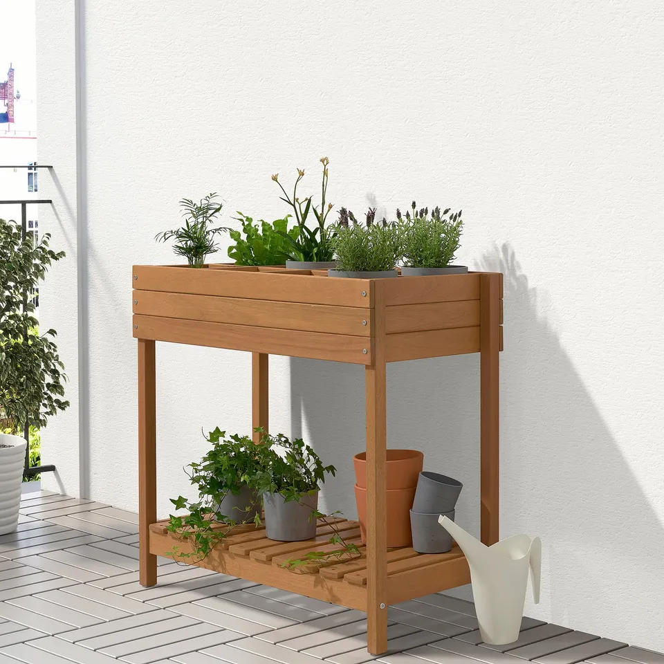 Wooden HATTHOLMEN plant stand holds multiple pots on two tiers, perfect for balcony gardening.