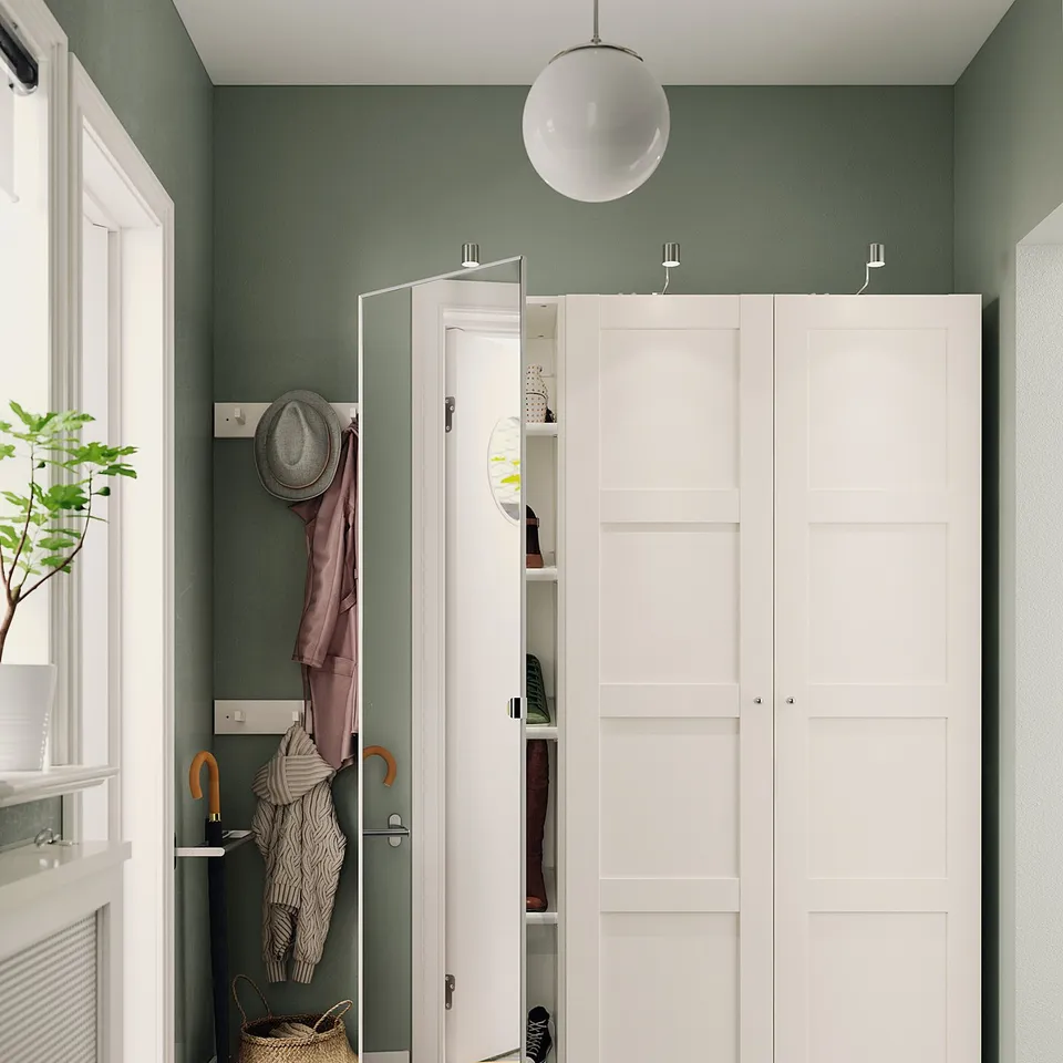 Modern entryway with white wardrobes and shoe storage. Green walls, dark stone floor.