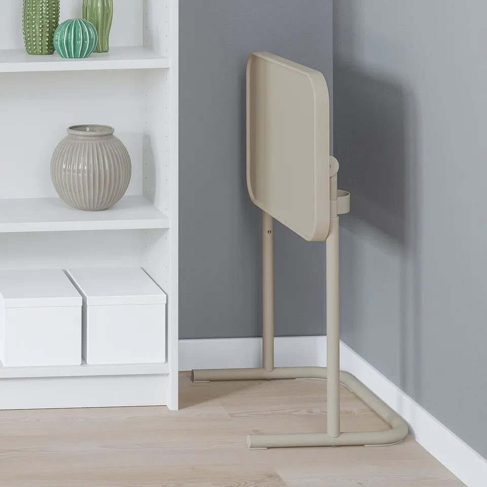 Beige laptop stand, adjustable, next to shelves with vases, against grey wall.