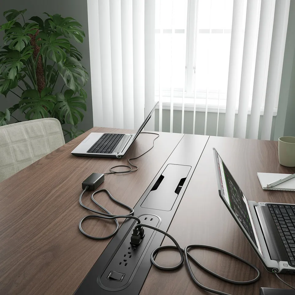 A modern conference table with laptops and plants. Built-in power outlet & cable management.