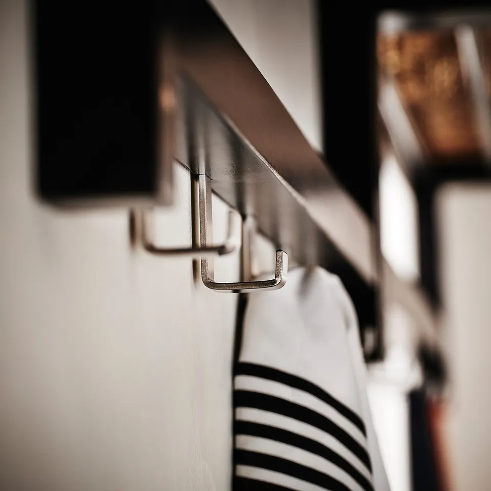 Metal hooks on wooden rail, hanging striped towel, showcasing TJUSIGs durable and stylish design.