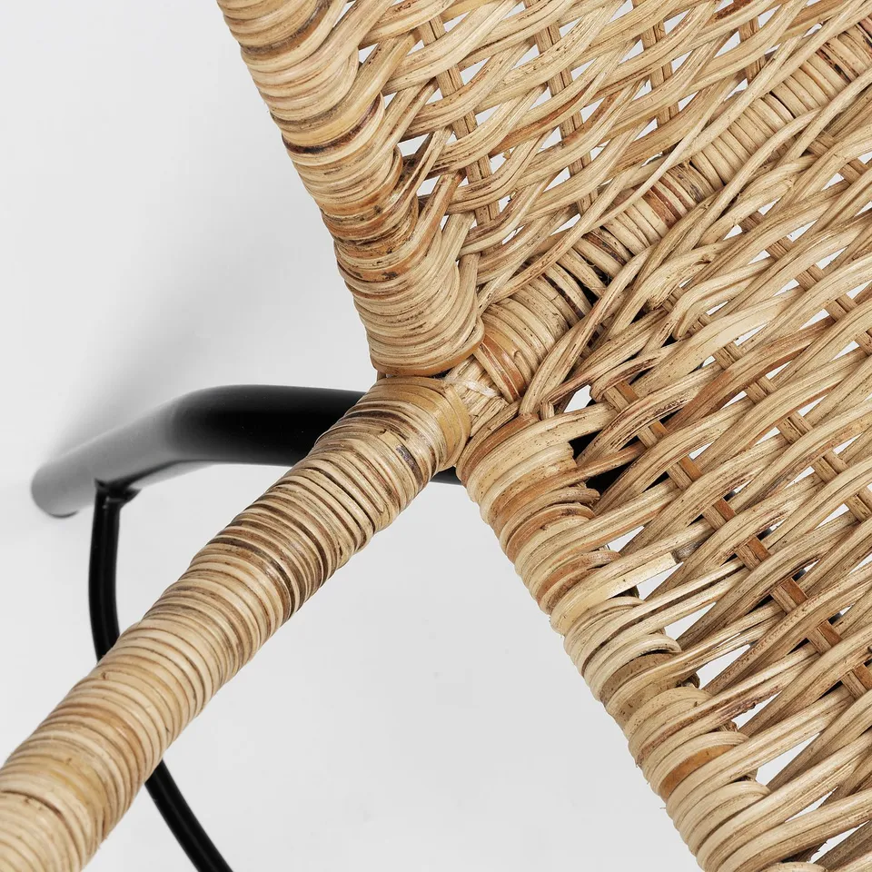 Wicker chair close-up: intricately woven natural rattan with sleek black metal armrests.