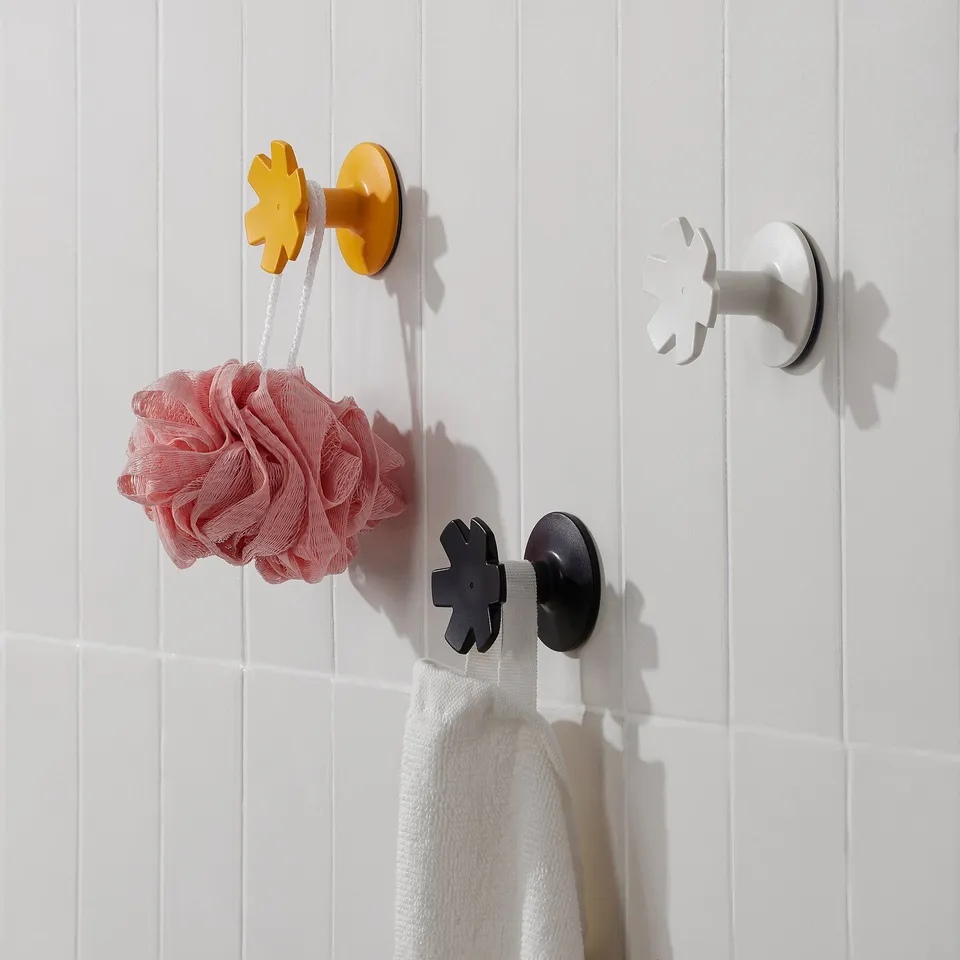 Colourful snowflake hooks on white wall hold pink bag and white towel.