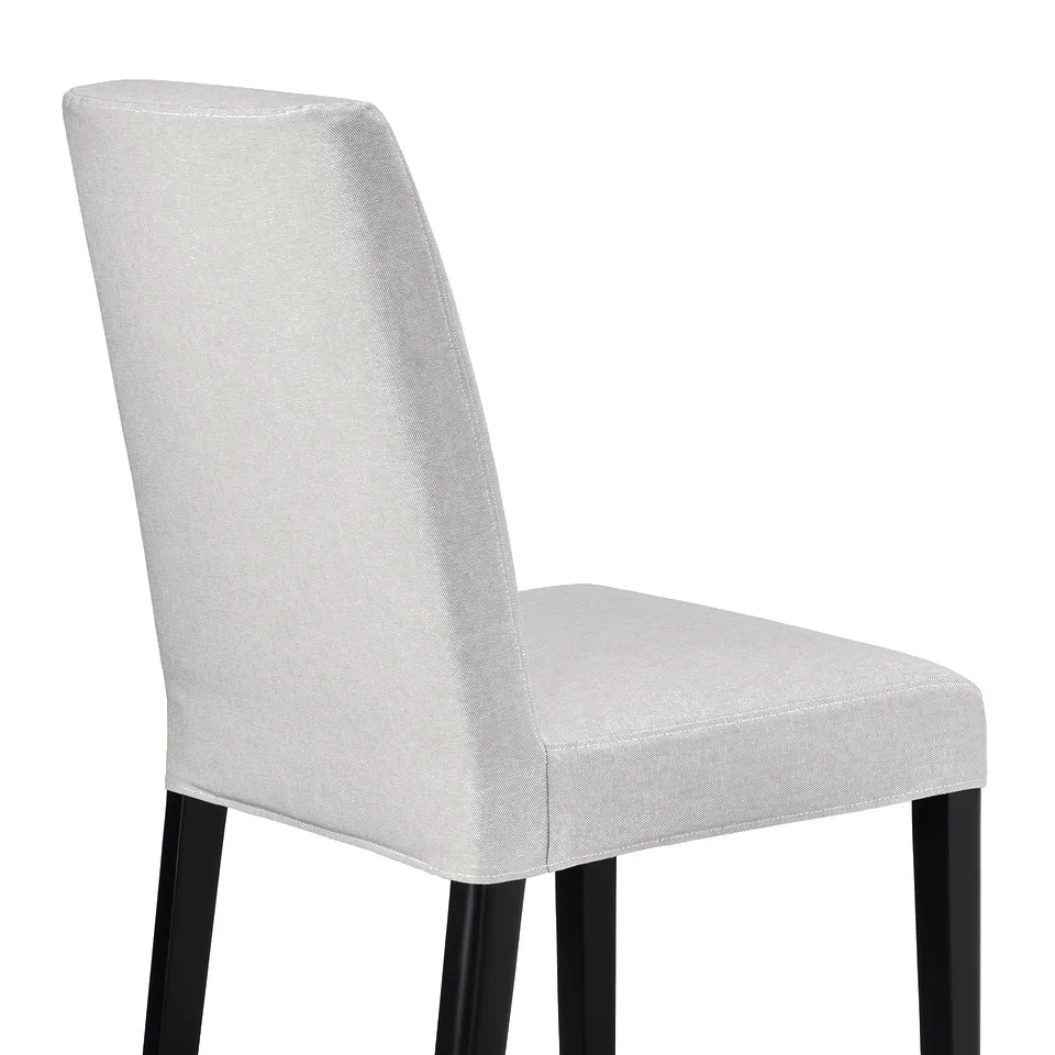 White upholstered chair with tall, curved back and black metal legs, designed for comfort and style.