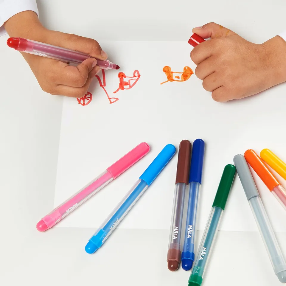 Image depicts children drawing with colourful markers on white paper. Various MÅLA markers lie nearby.