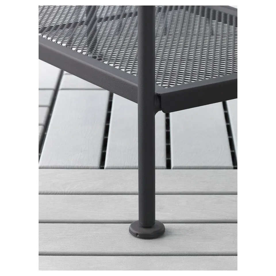 Black outdoor metal furniture with perforated seat, standing on light grey wooden decking, showcasing stability and durability.