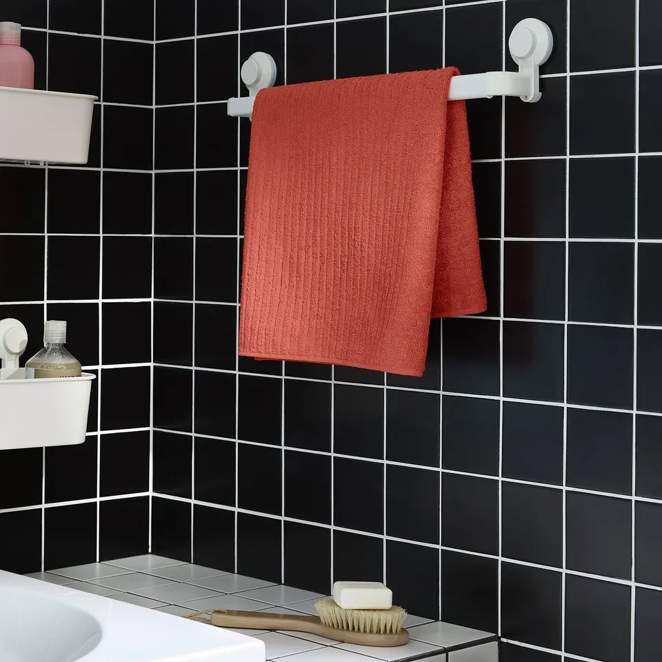 Red VÅGSJÖN towel on suction cups in bathroom.