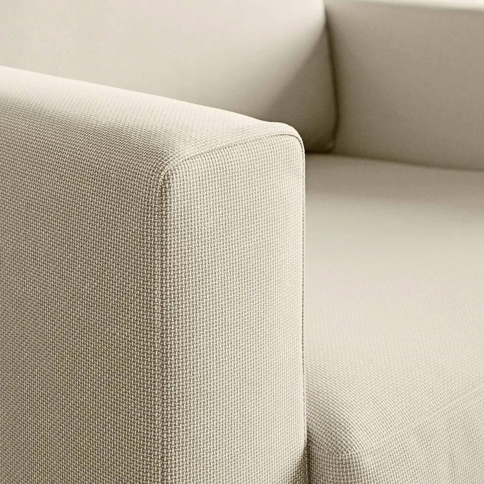 Close-up of a cosy, upholstered armchair corner showcasing high-quality, textured fabric and supportive cushioning.