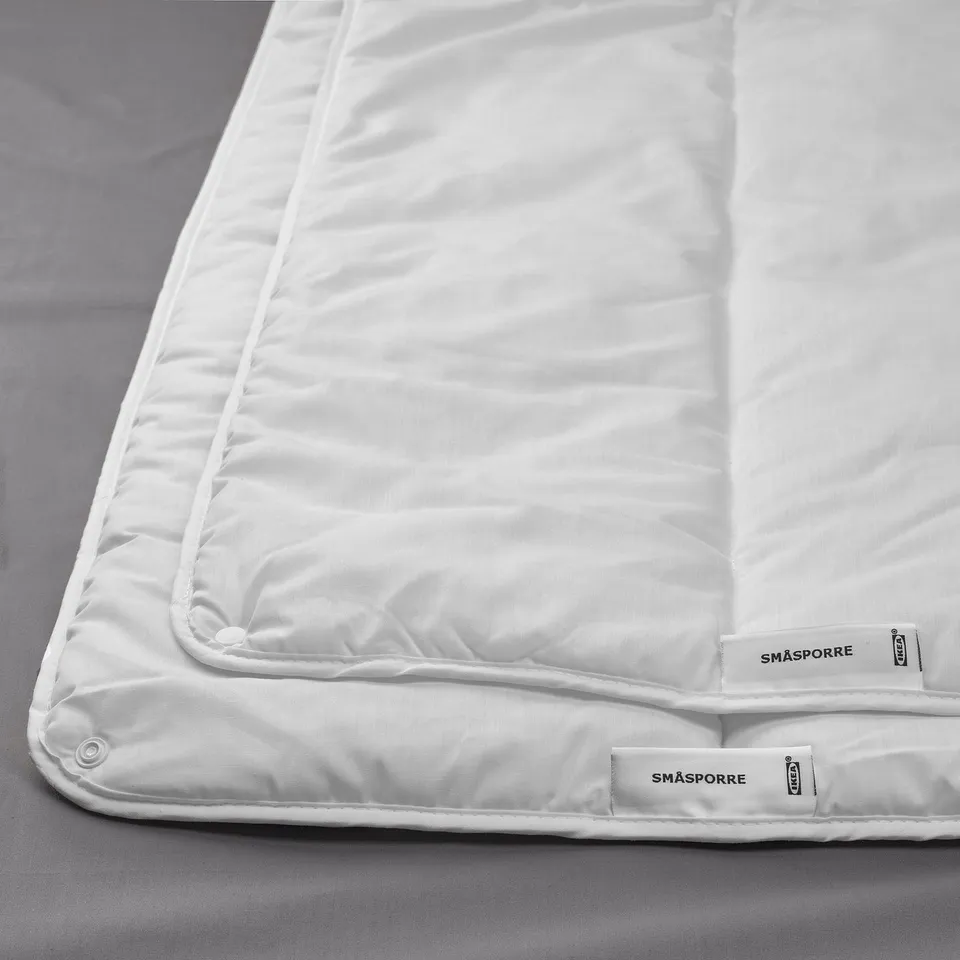 White SMÅSPORRE duvet with precise stitching on bed.